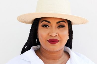 Rachel cargle wearing a white shirt an a cream colored hat with a white background